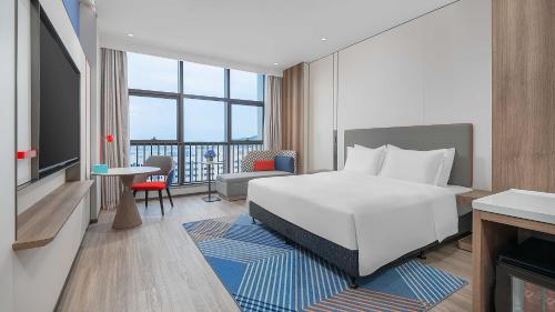 a hotel room with a white bed and a balcony at Holiday Inn Express Foshan Shunde Lecong by IHG in Shunde