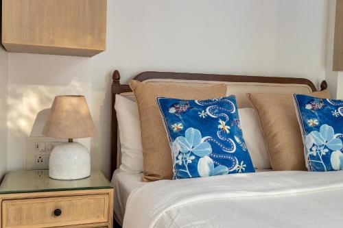 a bed with blue pillows and a lamp on a night stand at Villa Stairway to Heaven by tisyastays in Candolim