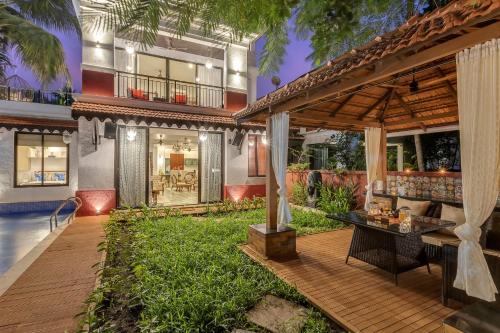 an outdoor patio with a wooden deck and a house at Villa Stairway to Heaven by tisyastays in Candolim
