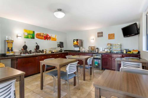 uma cozinha com mesas e cadeiras de madeira e uma televisão em Quality Inn & Suites St Augustine Beach Area em Saint Augustine Beach