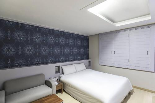 a bedroom with a white bed and a couch at Boryeong BonGaya Hotel in Boryeong