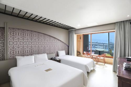 a hotel room with two beds and a balcony at Boryeong BonGaya Hotel in Boryeong