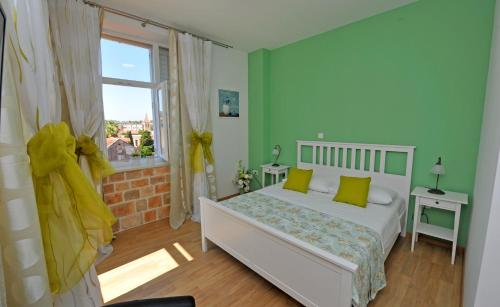 a bedroom with a bed with green walls and a window at Luxury Rooms Nirvana in Split
