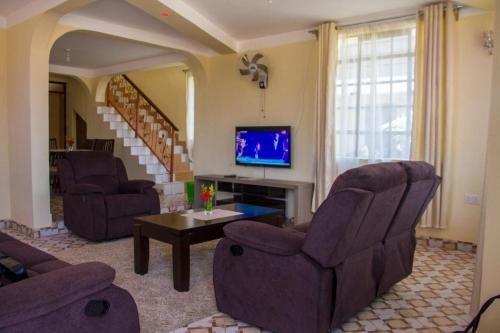 a living room with two chairs and a tv at Desa Homes in Voi