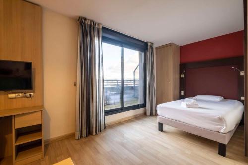 a bedroom with a bed and a large window at Clarion Aparthotel Toulouse Blagnac Airport in Blagnac