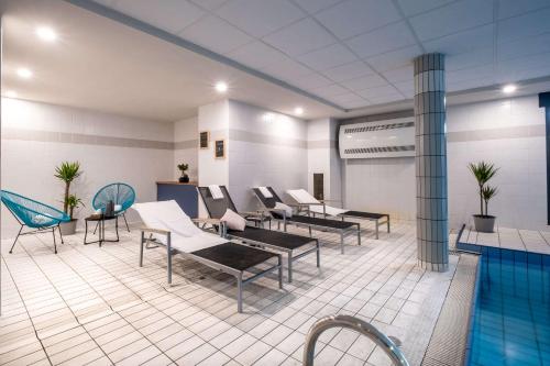 a pool room with chairs and a swimming pool at Clarion Aparthotel Toulouse Blagnac Airport in Blagnac