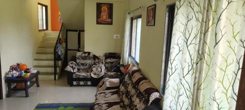 a living room with a couch and a staircase at Neelam Gardens in Nashik