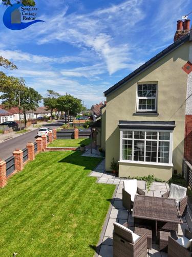 a backyard with chairs and a lawn with a house at Seaglass Cottage - Redcar in Redcar