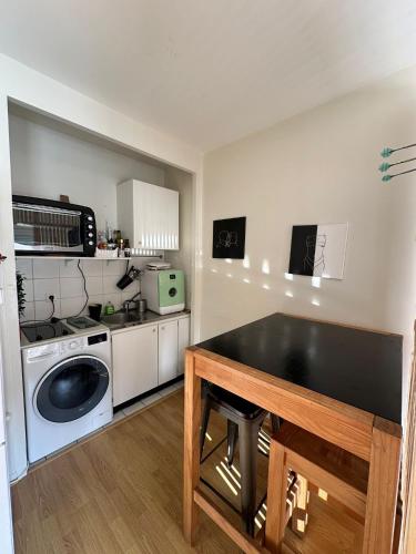une cuisine avec une table et une machine à laver dans l'établissement Studio cosy coeur paris - quartier Opéra, à Paris
