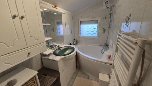 une salle de bain avec une baignoire et un lavabo et une baignoire dans l'établissement Maison RoseMary 2 Chambres à 10 minutes de Rouen, à Amfreville-la-Mi-Voie