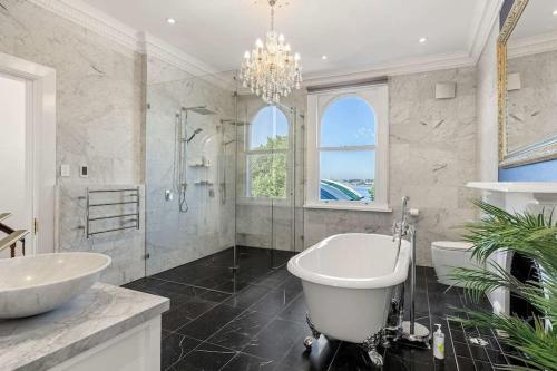 a white bathroom with a tub and a sink at Elegant 6-Bed Home with Harbour Views in Sydney
