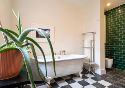 a bathroom with a tub and a potted plant at The Emporium - Stylish 2BD in central Winchcombe in Winchcombe