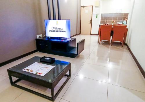 a living room with a tv and a table in a room at Bayou Lagoon Park Resort in Melaka