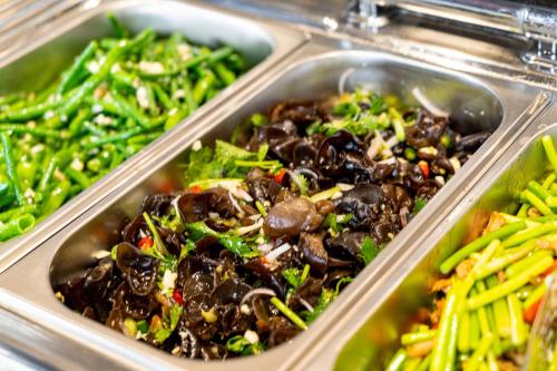 two metal trays of food with vegetables in them at Wuyu Hotel - Chongqing Liangjiang Happiness Plaza & Xingfu Square & GuangdianYuan metro in Chongqing