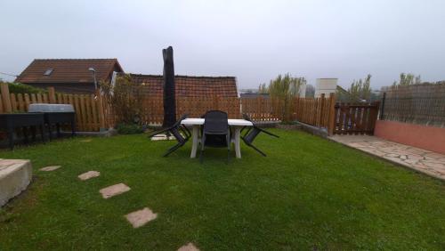 une table et une chaise dans la cour dans l'établissement Maison RoseMary 2 Chambres à 10 minutes de Rouen, à Amfreville-la-Mi-Voie