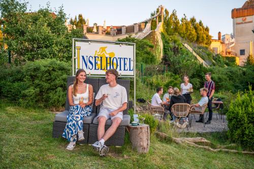 a man and woman sitting on a chair in the grass at Inselhotel Rügen in Göhren