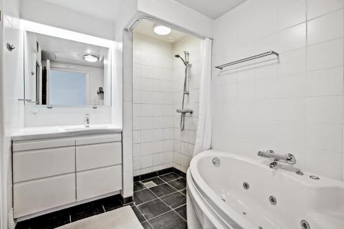 a white bathroom with a tub and a sink at Beautiful Two Story Apartment With Panoramic Views Of Ebeltoft Bay in Ebeltoft