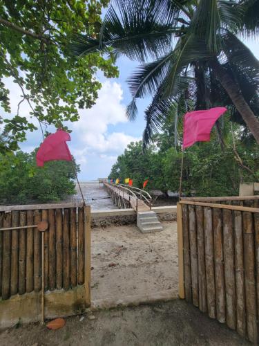 a wooden fence on the beach with pink flags at Bamboo House in Roxas