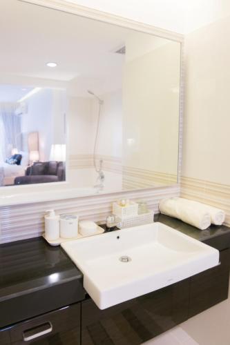 a bathroom with a white sink and a large mirror at Mansion28 Dharmawangsa Serviced Apartment in Jakarta