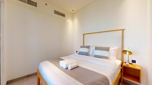 a white bedroom with a large bed with white pillows at The Community Jumeirah Village in Dubai