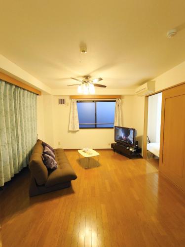 a living room with a couch and a flat screen tv at honeys guest house elevator , wash machine, huge closet space, private bathroom, walk to skytree in 10 minutes in Tokyo