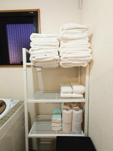 a closet with white towels on a shelf at honeys guest house elevator , wash machine, huge closet space, private bathroom, walk to skytree in 10 minutes in Tokyo