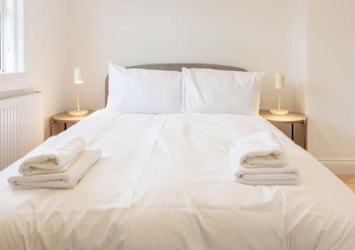 a white bed with two towels on top of it at Bright & Airy 2BD - 10 mins walk to Chelt Centre! in Cheltenham