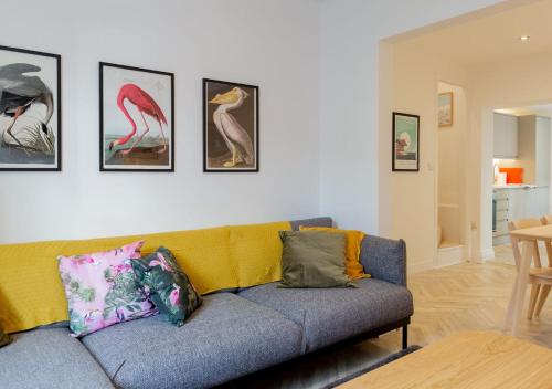 a living room with a couch and paintings on the wall at Bright & Airy 2BD - 10 mins walk to Chelt Centre! in Cheltenham