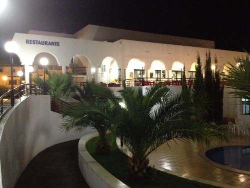 a building with palm trees in a courtyard at night at Rialgarve in Faro