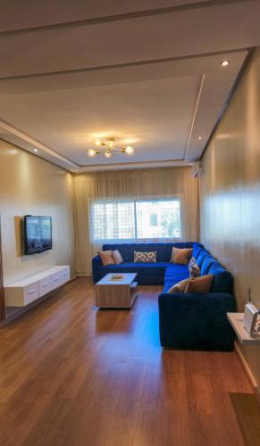 a living room with a blue couch and a tv at Le doux refuge - à 7 mn de la plage à pieds in Temara