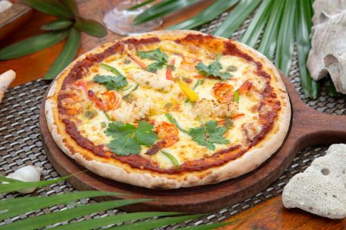 a pizza sitting on a wooden plate on a table at Eden Beach Resort By EHM in Koh Rong Sanloem