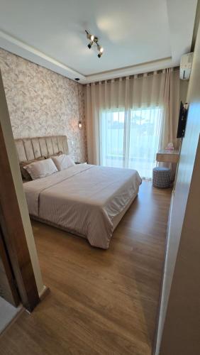 a bedroom with a large bed and a large window at Le doux refuge - à 7 mn de la plage à pieds in Temara