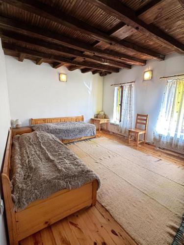 a bedroom with two beds and a wooden floor at Hadjigabarevata Kashta in Dalbok-Dol