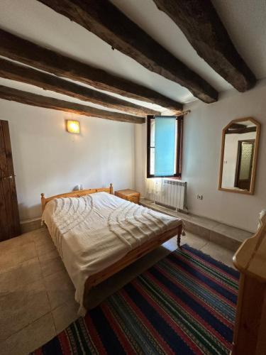 a bedroom with a bed and a mirror and a rug at Hadjigabarevata Kashta in Dalbok-Dol