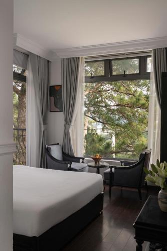 a bedroom with a bed and chairs and a large window at The Gate Boutique Hotel Đà Lạt in Da Lat