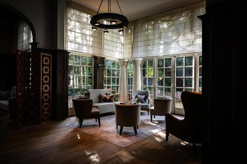 a living room with windows and a couch and chairs at Kasteel Kerckebosch in Zeist