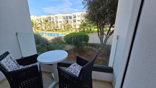 a balcony with a table and chairs and a view of a pool at Le doux refuge - à 7 mn de la plage à pieds in Temara