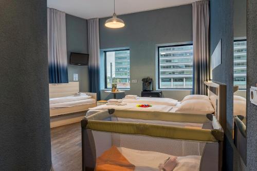a room with two beds and a room with windows at MEININGER Hotel Amsterdam City West in Amsterdam