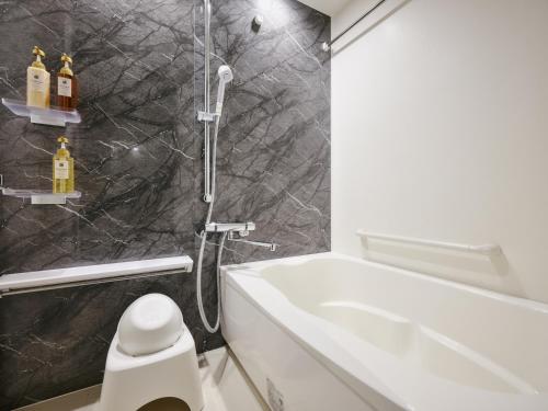 a bathroom with a shower and a toilet and a sink at MONday Apart Premium Ginza Shintomicho in Tokyo