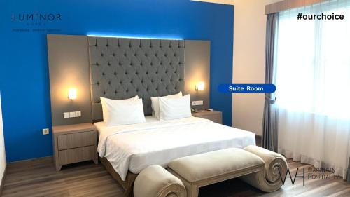 a bedroom with a large bed and a blue wall at Luminor Hotel Palembang by WH Free Massage 10 Minutes in Palembang