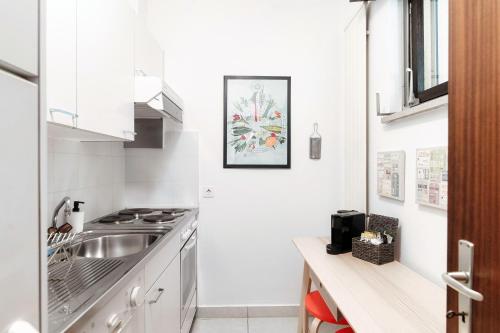 a white kitchen with a sink and a counter at City Escape by Quokka 360 - Close to Lugano Center in Viganello