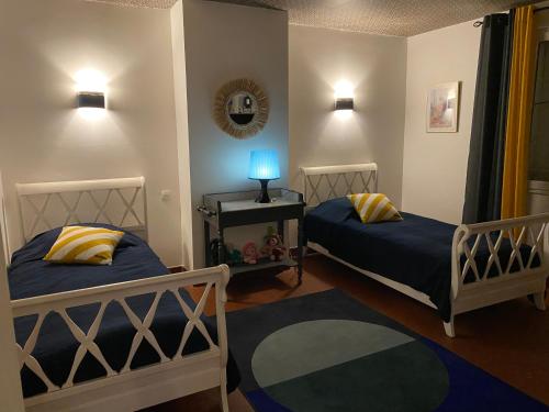 une chambre avec deux lits et une table avec une lampe dans l'établissement Maison Saint Roch, à Mouchan