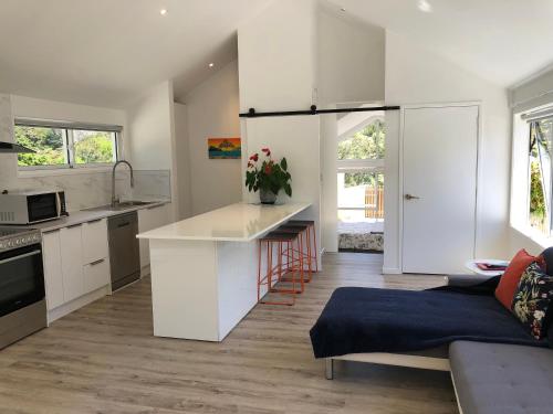 a kitchen with white cabinets and a kitchen island at Maraetai -Kererū Cottage - Whole House in Maraetai