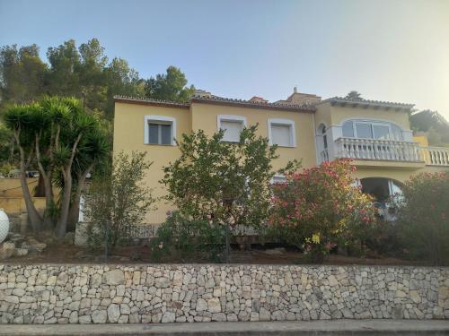 a large yellow house with a stone wall at Villa Mariposa in Casas Albardanera