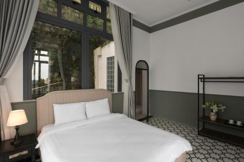 a bedroom with a large white bed and a window at The Gate Boutique Hotel Đà Lạt in Da Lat