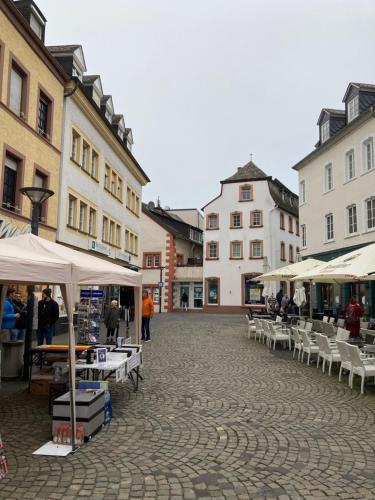 a street with tables and white umbrellas and buildings at Wohnen auf Zeit in Wittlich