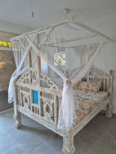 a white bed with a canopy in a room at Daffi giraffi House in Malindi