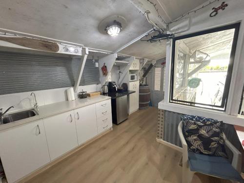 a kitchen with white cabinets and a large window at On the water boat House in Whangarei