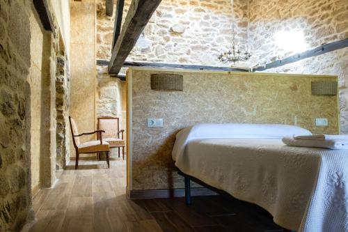a bedroom with a bed and a chair in a room at Casa do Comediante in Cerdeira