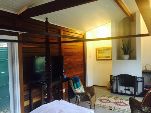 a living room with a tv and a couch and chairs at Casa da Ilha do Mel - Pousada de Charme in Ilha do Mel